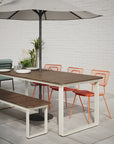 Styled outdoor shot of Bowen Communal Table in Walnut with Gloss White base. Umbrella table. Outdoor bench seating. Kansas City outdoor office furniture.