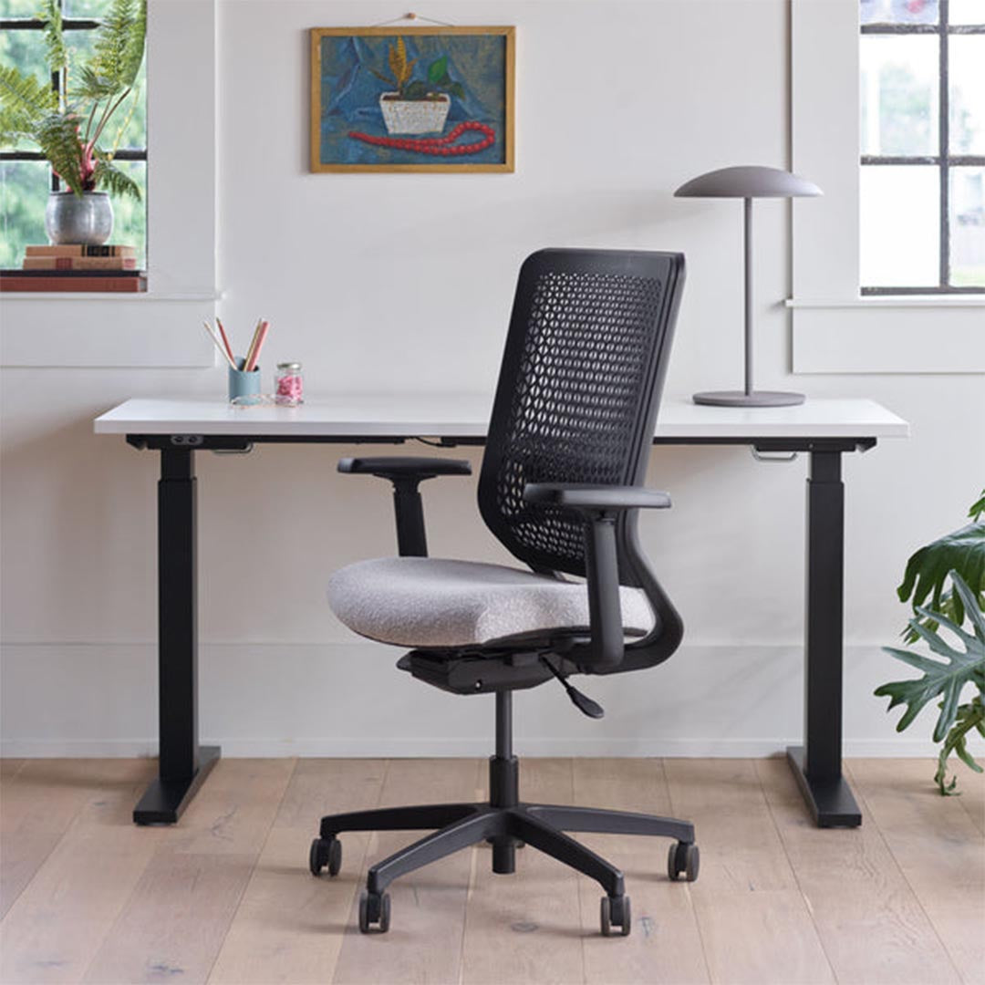 OFS Genus Office Desk Chair with Elastomer Back and height adjustable desk in cozy office with natural light, carbon frame with black nylon base, Kansas City Office Furniture